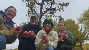 Grace and some FISH Food Bank Volunteers holding up a recent apple harvest.