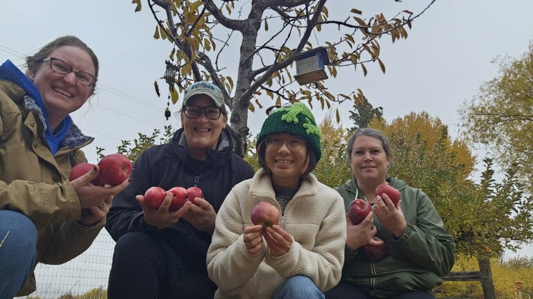 Grace and some FISH Food Bank Volunteers holding up a recent apple harvest.