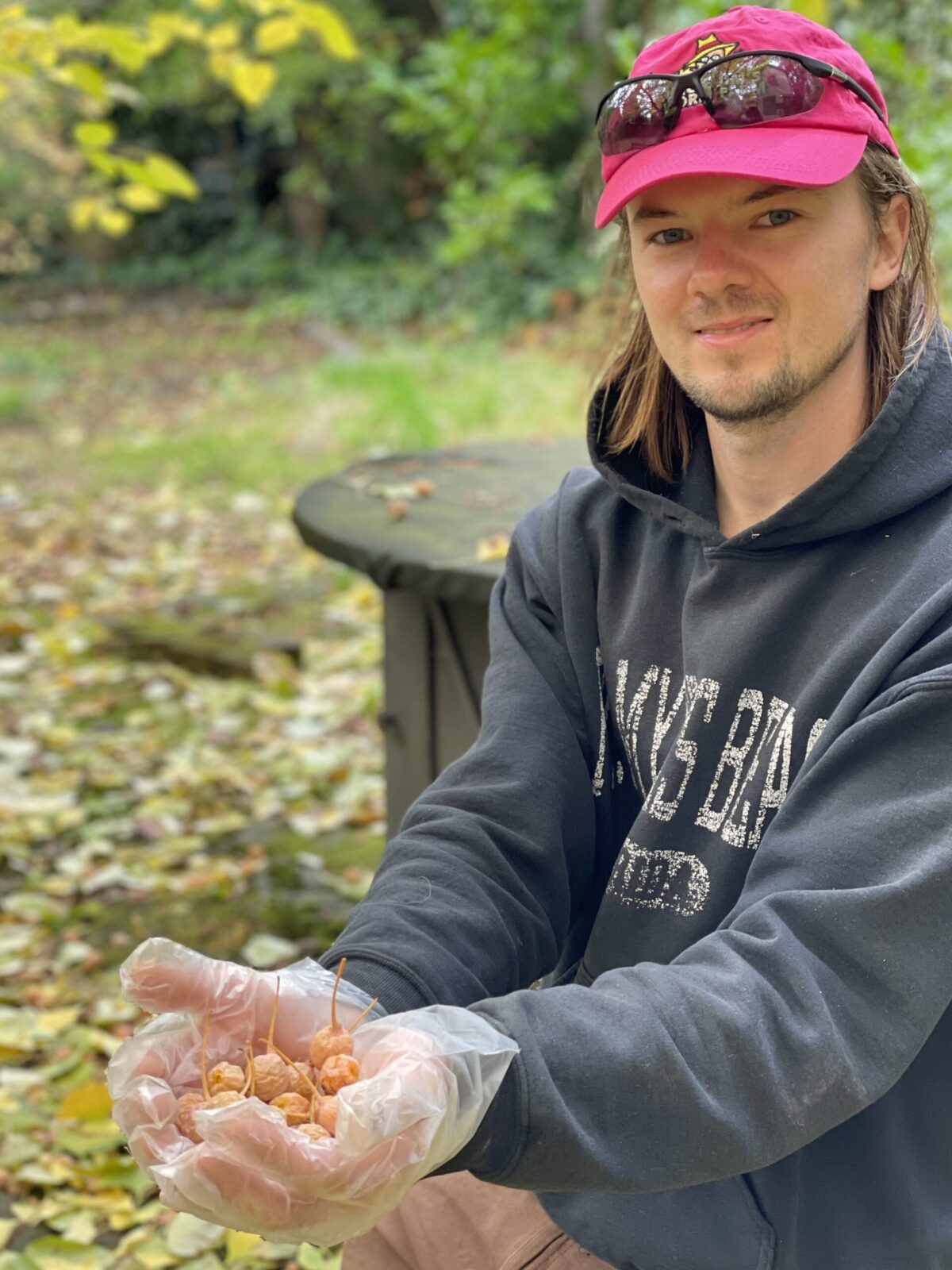 Owen Cooper is wearing a neon pink hat and showing off some ground cherries he harvested.
