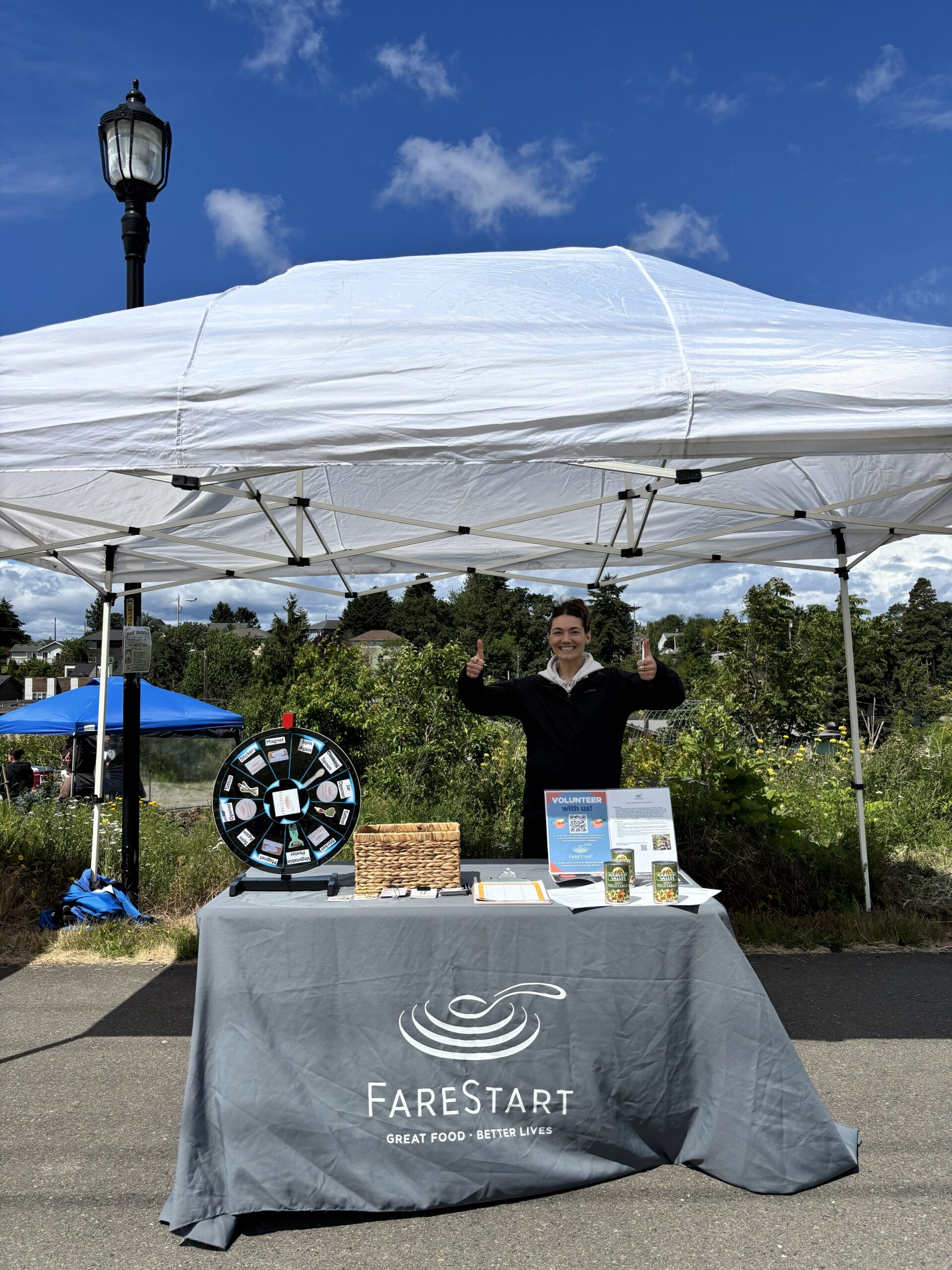 Sydney Shaw posing behind a Farestart branded table at a community event.